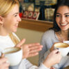 Tre venninner sitter på kafé og drikker kaffe