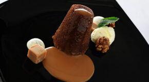 En sticky toffee pudding er pent dandert på en svart tallerken